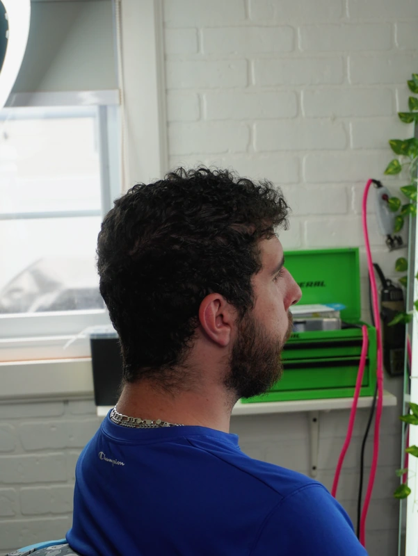 Client before his cut — curls grown out over the ears and down the neck